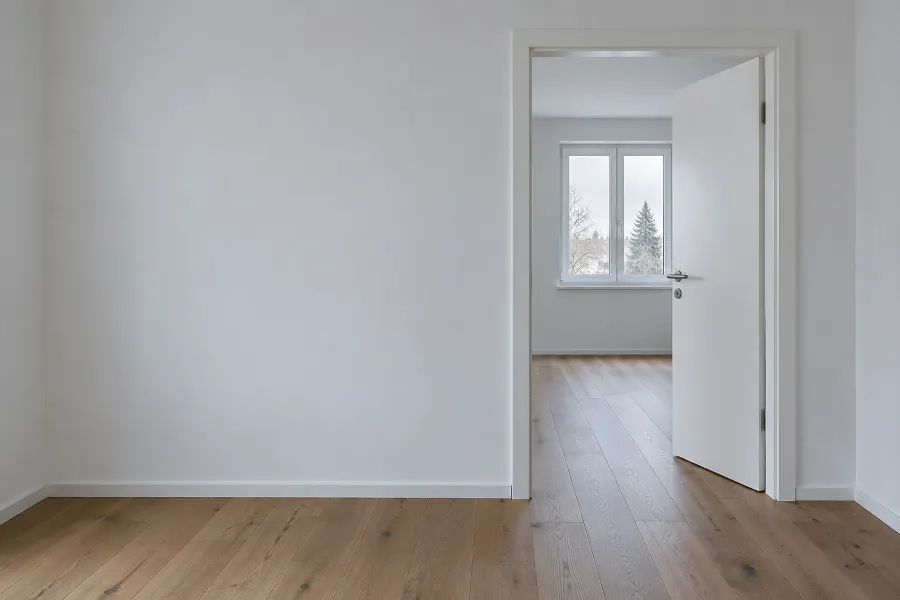 Weiße Innentür mit Edelstahldrücker, offen zu einem hellen Zimmer